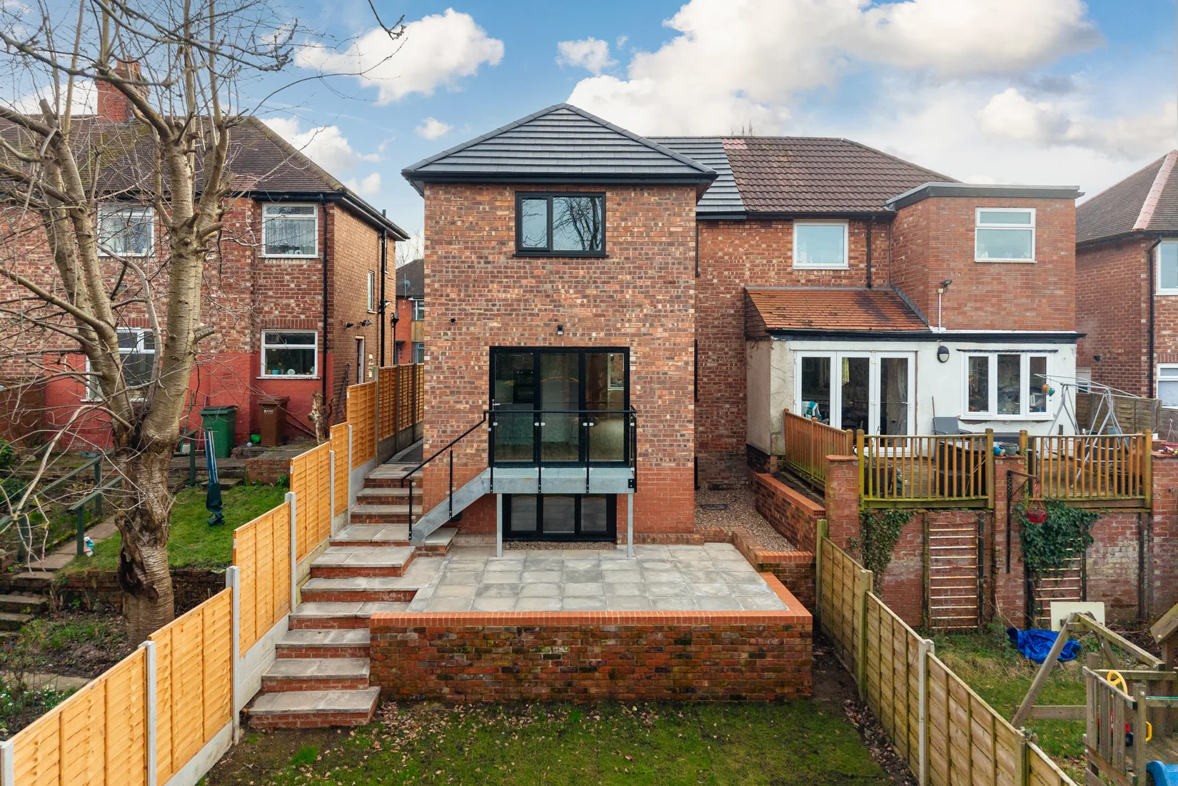 Rear of the renovated home with a raised patio and garden-level glazing